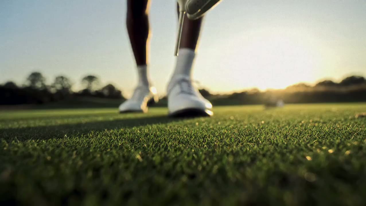 Close-up of a golfer at address on a sunlit green